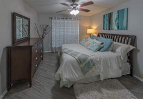 A bedroom with a bed, dresser, and ceiling fan.
