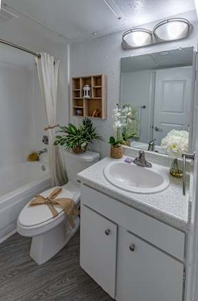 A white bathroom with a toilet, sink, and mirror.