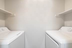 Two white washing machines in a laundry room.