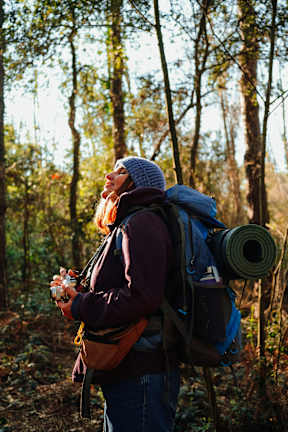 A woman with a backpack and camera in the woods.
