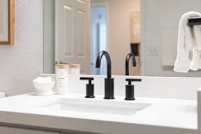A white sink with a black faucet and a white bowl with a white substance in it.
