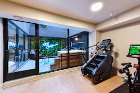A home gym with a treadmill, exercise bike, and a view of the outdoors.