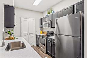 A kitchen with pantry, onyx cabinets, and stainless steel appliances at Bardin Greene apartments for rent in Arlington, TX.