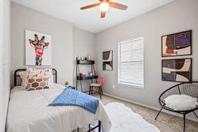 A bedroom with a bed, ceiling fan, a chair, and a window at Bardin Greene Arlington pet-friendly apartments.