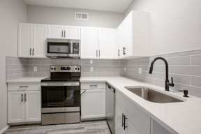 A kitchen with white cabinets and a black stove top oven.
