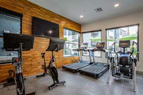 A gym with treadmills, exercise bikes, and a television.