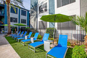 A row of blue lawn chairs are lined up on a patio.