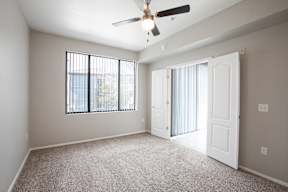 A room with a ceiling fan and a window with blinds.