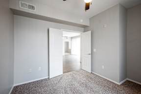 A room with a carpeted floor and a ceiling fan.