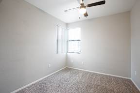 A room with a ceiling fan and a window with blinds.