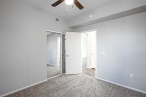 A room with a ceiling fan and two open doors.