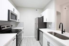 A kitchen with black appliances and white cabinets.