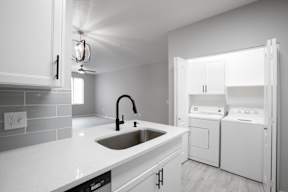 A modern kitchen with a white sink and appliances.