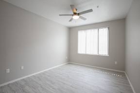 A room with a ceiling fan and a window with blinds.