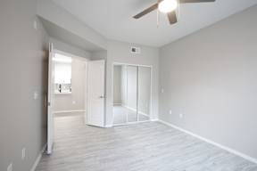 A room with a ceiling fan and a doorway leading to another room.