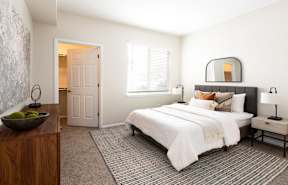 A bedroom with a large bed, a wooden dresser, and a bowl of fruit on the dresser.