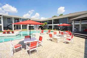 A patio with red cushioned chairs and tables.
