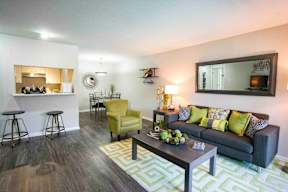 A living room with a grey couch, yellow chair, and a green rug