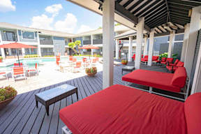 A patio with red cushioned chairs and tables.