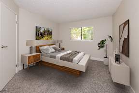 A bedroom with a bed, nightstand, and a painting on the wall.