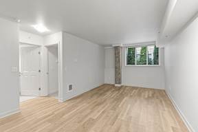 A room with wooden flooring and a window with blinds.