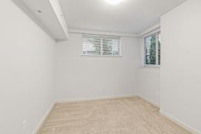 A room with a carpeted floor and a window with blinds.