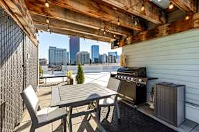 A patio with a table, chairs and a grill.