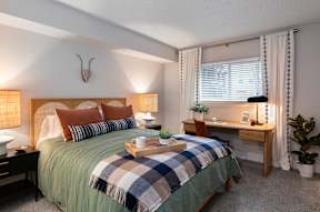 A bedroom with a bed, desk, and chair.