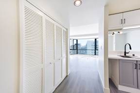A kitchen with white cabinets and a window with blinds.
