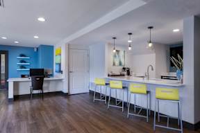 A kitchen with a bar area and a desk with a computer.
