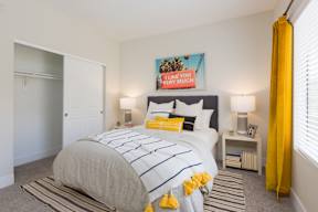 A bedroom with a bed, two lamps, and a yellow curtain.