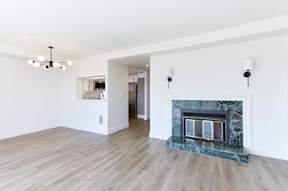 A living room with a fireplace and a kitchen in the background.