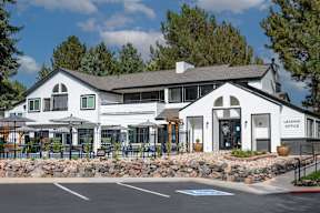 A white building with a black roof and a sign that says "Leasing Office" is in front of some trees.