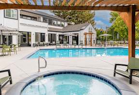 A pool area with a hot tub and a building in the background.