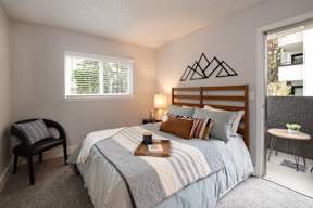 A bedroom with a bed, a chair, and a window.