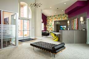 A modern living room with a black bench and a chandelier.