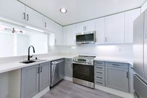 A modern kitchen with white cabinets and stainless steel appliances.