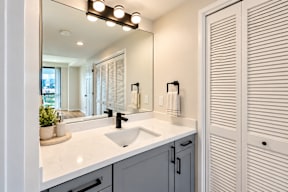 A bathroom with a sink, mirror, and lighting fixture.