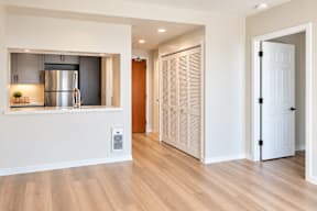 A kitchen with a refrigerator, wooden floors, and a white door.