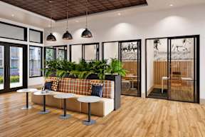 A room with a couch, plants, and a wooden floor.
