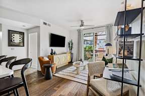 A living room with a flat screen TV and a glass door leading to a balcony.