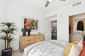 A bedroom with a bed, dresser, and a plant.
