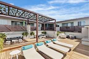 A sunny day at the rooftop patio with white lounge chairs and blue cushions.
