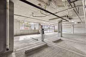 A parking garage with a concrete floor and walls, and a concrete pillar on the left.