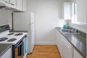 A kitchen with a stove, refrigerator, and sink.