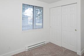 A room with a window covered by blinds and a white door.