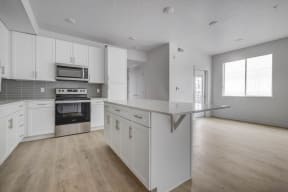 an empty kitchen with white cabinets and stainless steel appliances