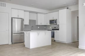 an empty kitchen with white cabinets and stainless steel appliances