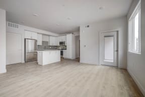 the living room and kitchen of an apartment with white walls and wood floors