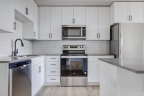 a white kitchen with stainless steel appliances and white cabinets